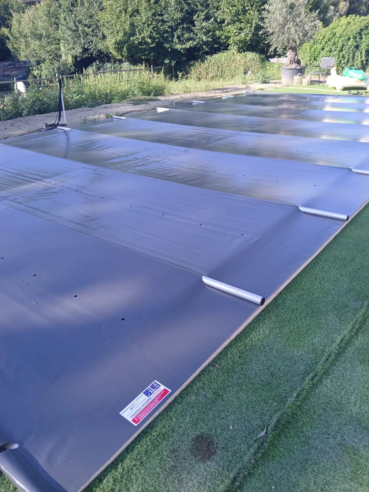 Couverture à barres sur une piscine bordée de gazon